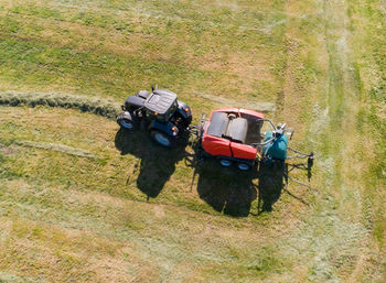 Black tractor with a red straw chamber press during the straw harvest on a mown field