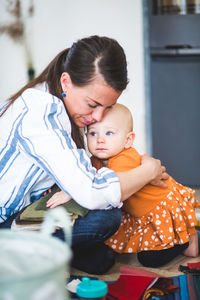 Multi-tasking fashion designer embracing loving daughter at home