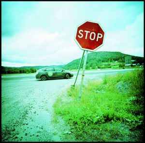 Information sign on road amidst field against sky