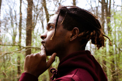 Side view of thoughtful young man in forest