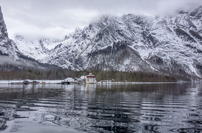 Scenic view of lake by snowcapped mountains against sky