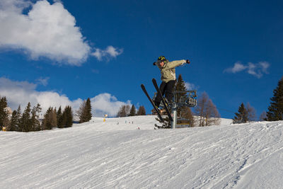 Man skiing on snow covered land against sky