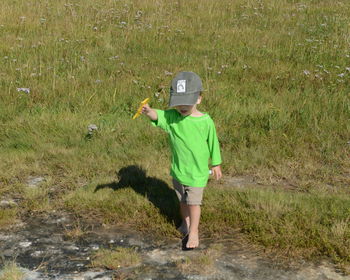 Boy walking on grassy field during sunny day