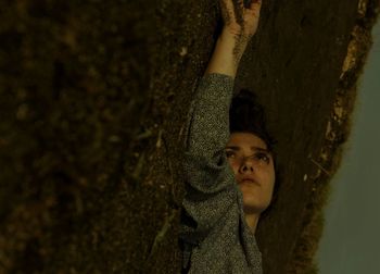 Close-up of woman holding soil while standing by tree trunk