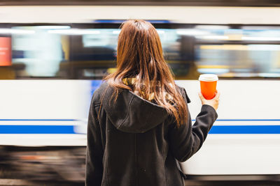 Rear view of a woman against blurred bus