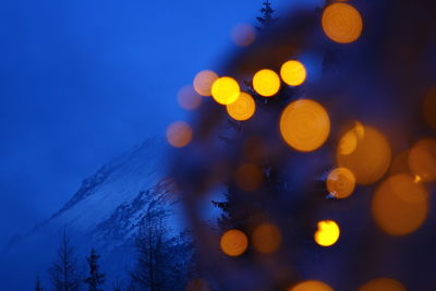 Defocused image of illuminated tree against sky at night