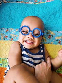 Portrait of a smiling boy sitting laying on quilt