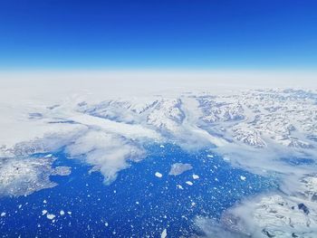 Aerial view of snowcapped mountain against blue sky