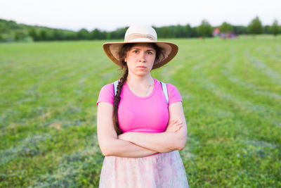 Portrait of teenage girl wearing hat standing on field