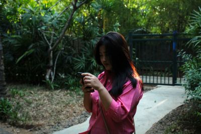 Full length of teenage girl using mobile phone in park