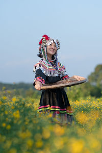 Woman with umbrella on field against sky