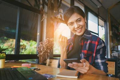Portrait of smiling young woman using mobile phone