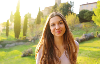 Portrait of smiling young woman standing against plants