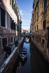 Canal amidst buildings in city against sky