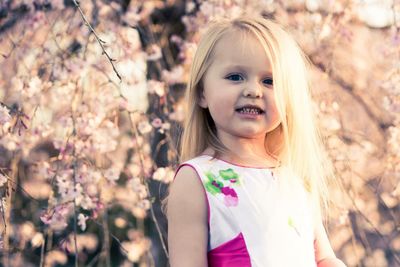 Portrait of cute girl standing against cherry blossom at park