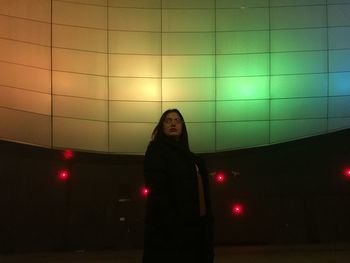 Portrait of woman standing against illuminated wall