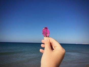 Midsection of person holding umbrella against sea