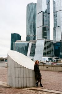 Full length of young woman standing by built structure in city