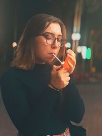 Young woman lighting cigarette at night