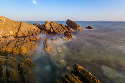 Rock formations in sea against sky