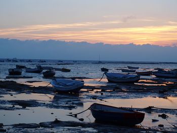 Boats moored in calm sea at sunset