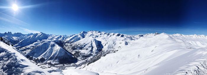 Scenic view of snowcapped mountains against blue sky