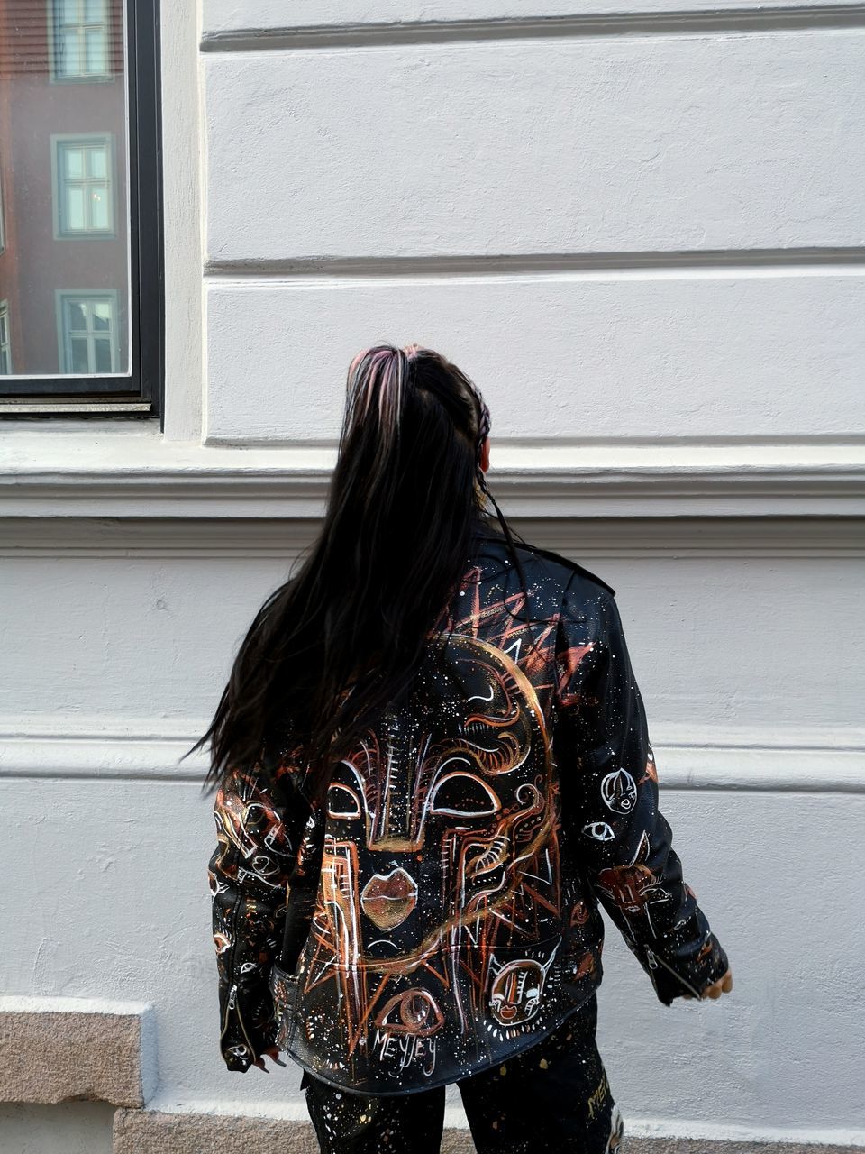 one person, black, rear view, adult, architecture, clothing, women, fashion, hairstyle, long hair, three quarter length, lifestyles, standing, day, built structure, jacket, young adult, window, spring, casual clothing, outerwear, building exterior, person, outdoors, leisure activity, wall - building feature, leather, arts culture and entertainment