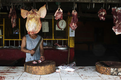 Midsection of butcher cutting meat at butcher shop