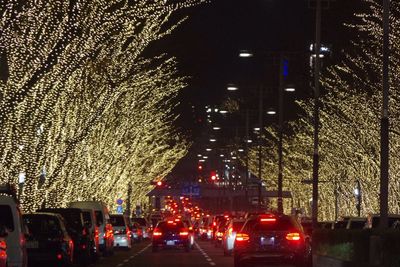 Cars on road against illuminated city at night