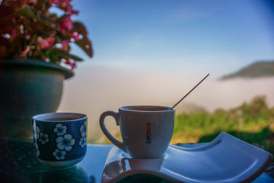 Close-up of coffee cup on table against blue sky