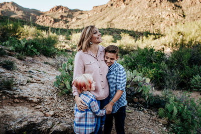 Mom smiling and hugging her two non binary children