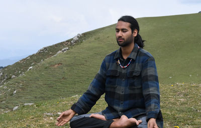 A young indian man practicing yoga in lotus pose, padmasana with gyan mudra  in the mountain.