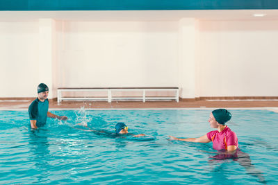 Boy learning to swim in pool with teacher