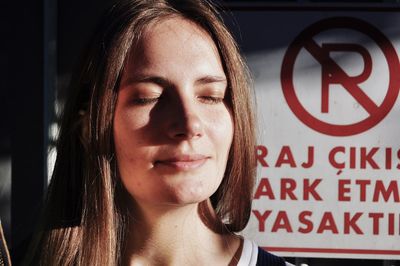 Close-up of young woman by information sign