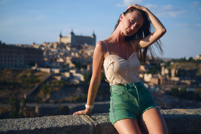 Portrait of young woman wearing bikini while standing against sky