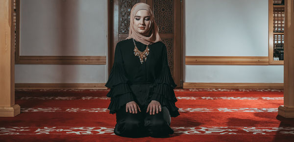 Full length of woman standing against red wall