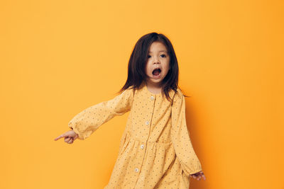 Cute girl with mouth open in front of orange background