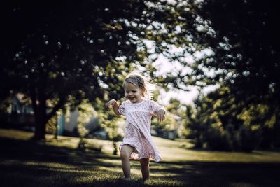 Full length of cheerful baby girl walking on grassy field