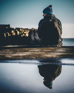 Rear view of man looking at lake against sky