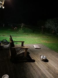 Empty chairs and table in yard at night