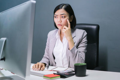 Young woman using mobile phone while sitting on table