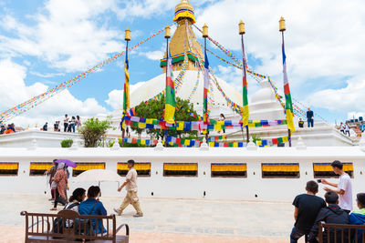 People at amusement park against sky