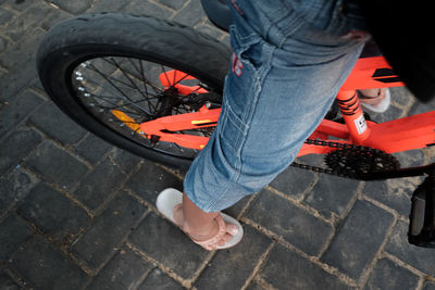 Low section of man with bicycle tire on footpath