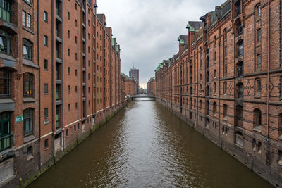 Canal amidst buildings in city against sky
