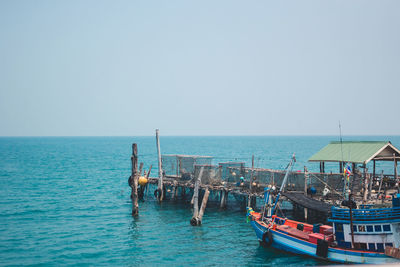 Fishing boats in sea against clear sky