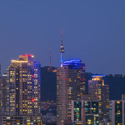 Illuminated buildings in city against clear sky at night