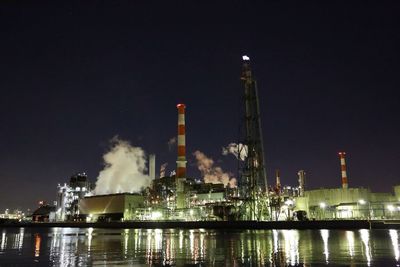 Panoramic view of illuminated factory against sky at night