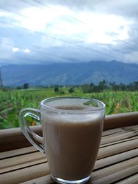 Coffee cup on table against mountains