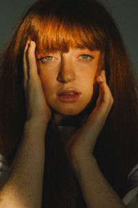 Portrait of young woman against black background