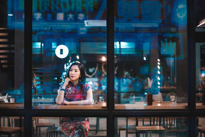 Woman sitting at illuminated restaurant